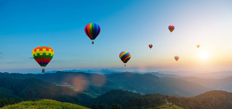 Colorful hot air balloons flying over Cappadocia mountains at sunset