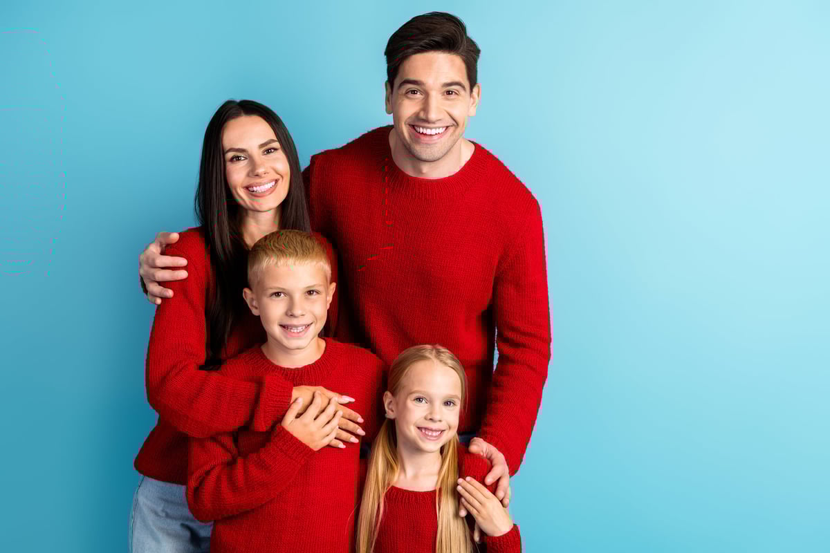 Smiling parents and their children in festive red sweaters bonding